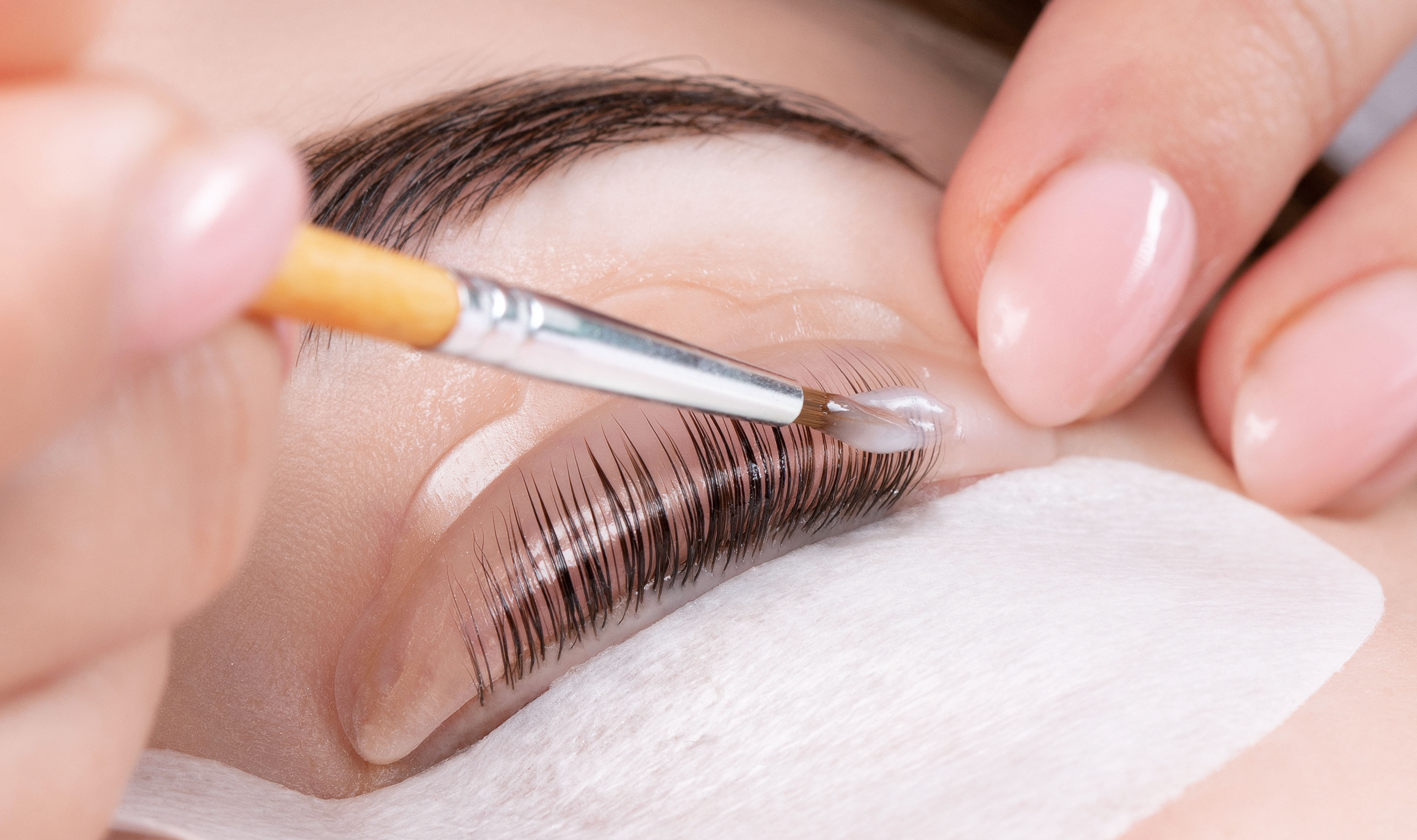 Make-up artist makes the procedure of lamination and dyeing of eyelashes to a beautiful woman in a beauty salon. Eyelash extensions. Eyelashes close-up